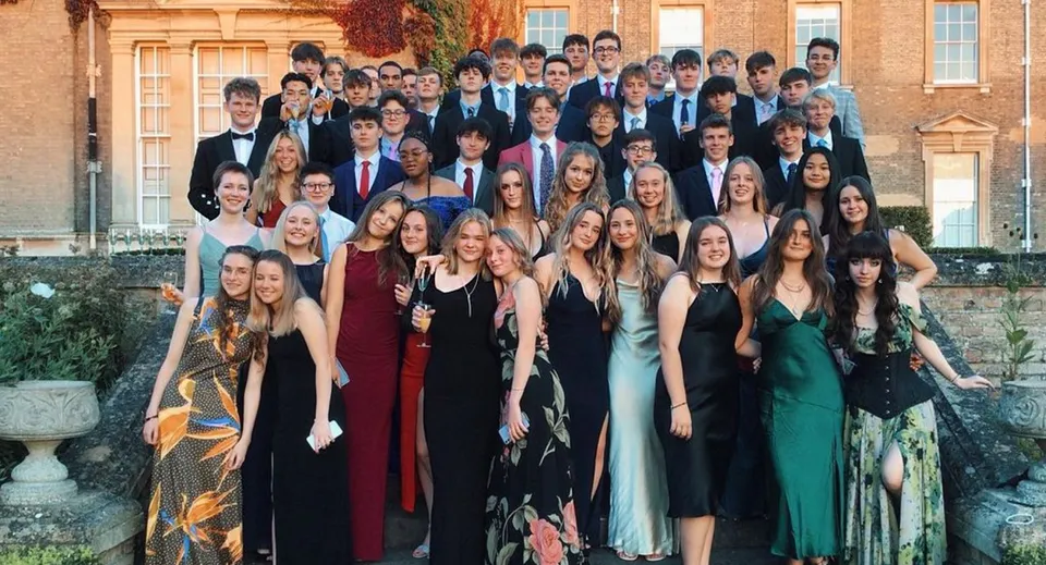 Un gruppo di studenti e studentesse della Culford School in abiti formali davanti a un edificio storico del campus.