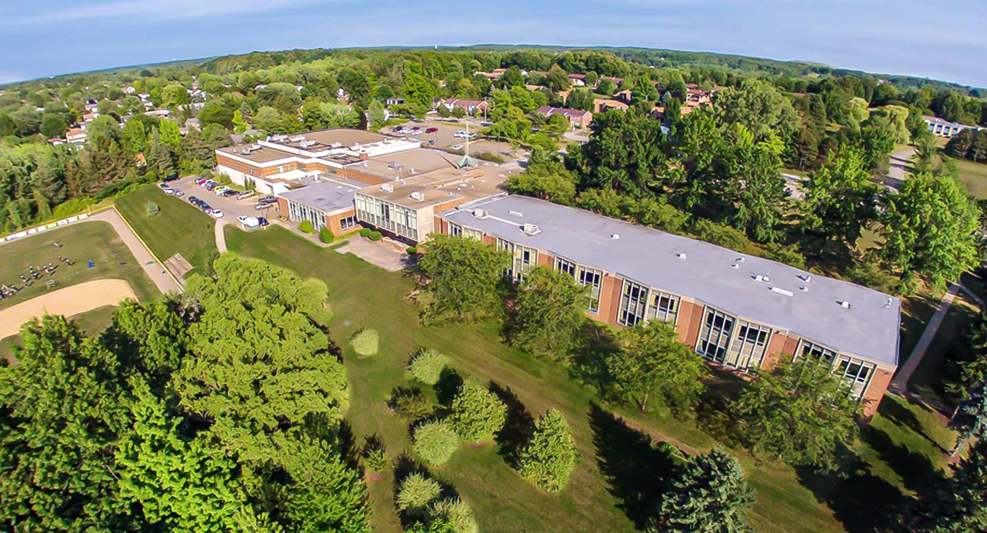 L'ampio campus della Mercyhurst Prep School si estende tra edifici e paesaggi verdi tra colline sotto un cielo blu.