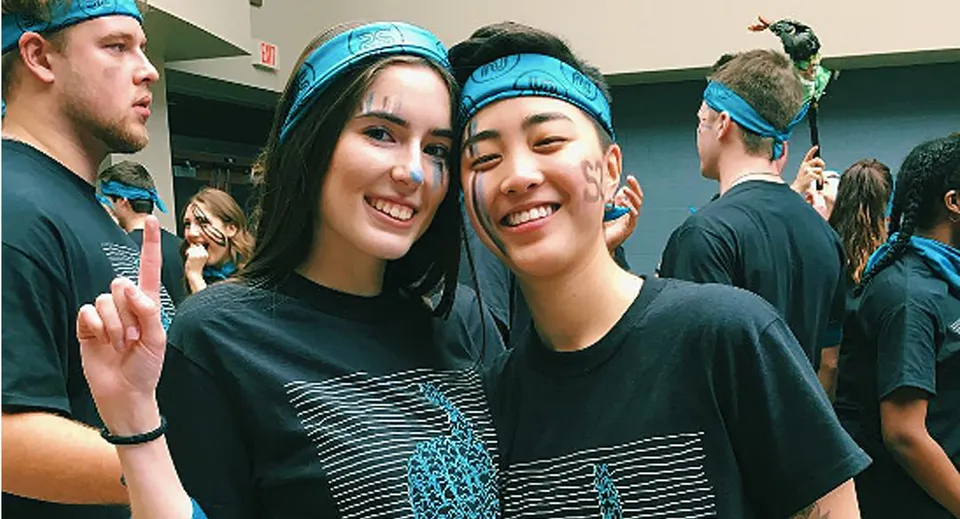 Due studentesse con fascette blu per i capelli posano insieme in uno spazio interno della Northview Heights Secondary School.