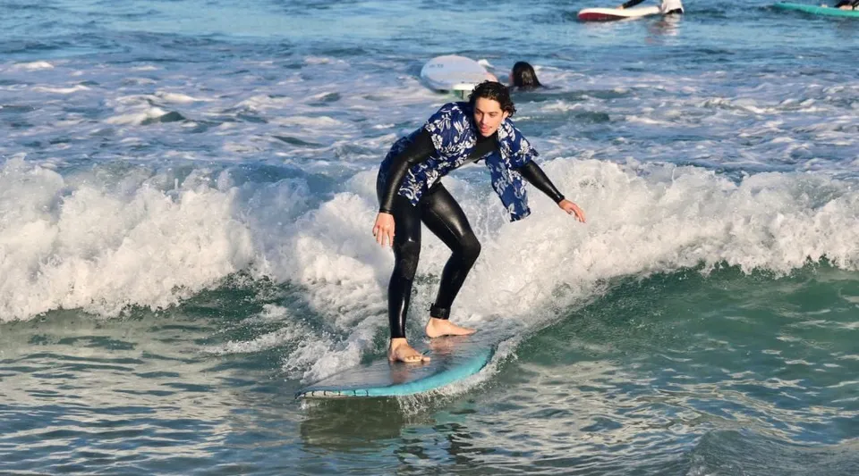 Una persona in muta fa surf su un'onda nell'oceano lungo la costa vicino alla Mount Lawley Senior High School.
