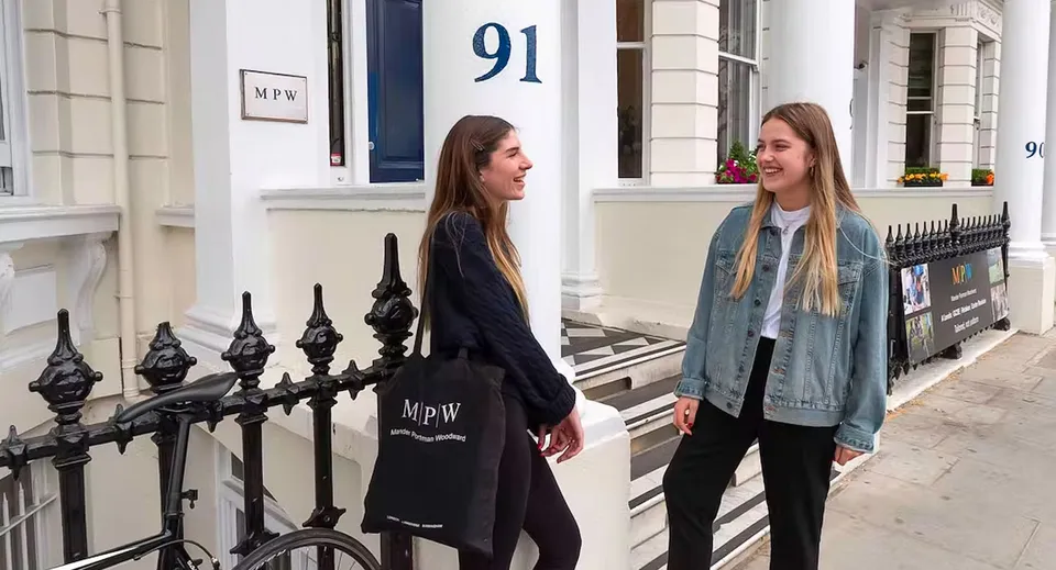 Due studentesse sono in piedi davanti a un edificio con il numero 91 nel campus della MPW London e chiacchierano.