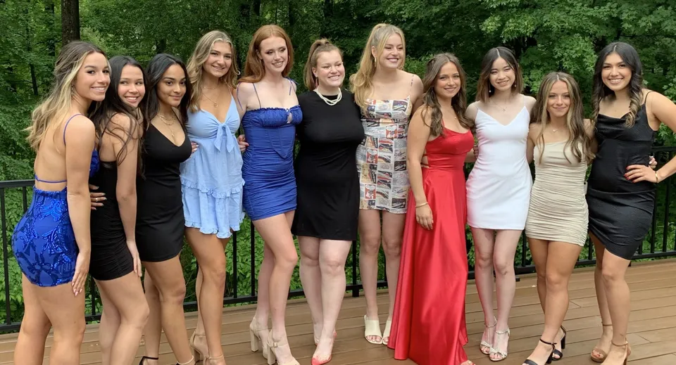 Un gruppo di giovani donne in abiti colorati posa insieme nel verde all'interno del campus del Brooke House College.