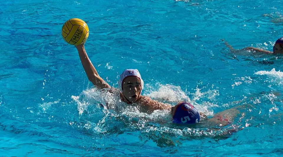 Una persona nuota nella piscina della Bishop Garcia Diego High School tenendo in mano una palla gialla.