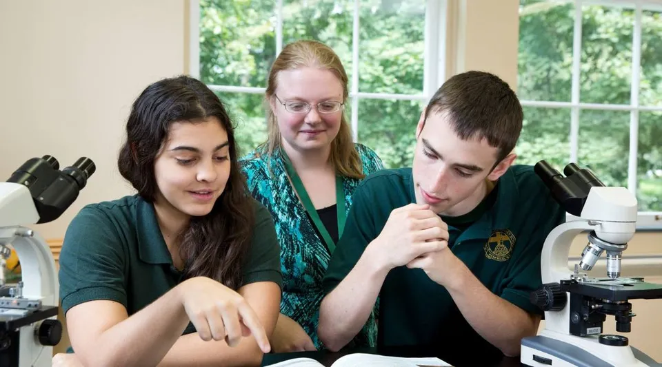 Tre studenti siedono insieme in un'aula studio della Charles Finney School con vista sul verde circostante.