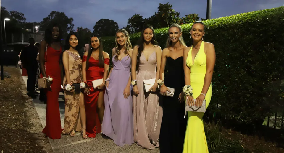 Un gruppo di studentesse di Hurtwood House in eleganti abiti da sera davanti a uno sfondo verde di notte.
