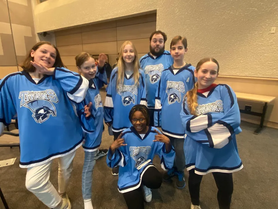 Un gruppo di studenti della École secondaire publique Gisèle-Lalonde indossa maglie blu e posa insieme nello spogliatoio.