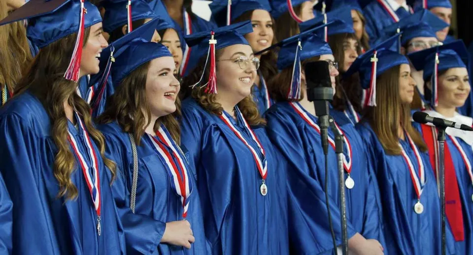 I diplomati della Oakridge Secondary School posano insieme in toga blu durante una cerimonia di diploma.