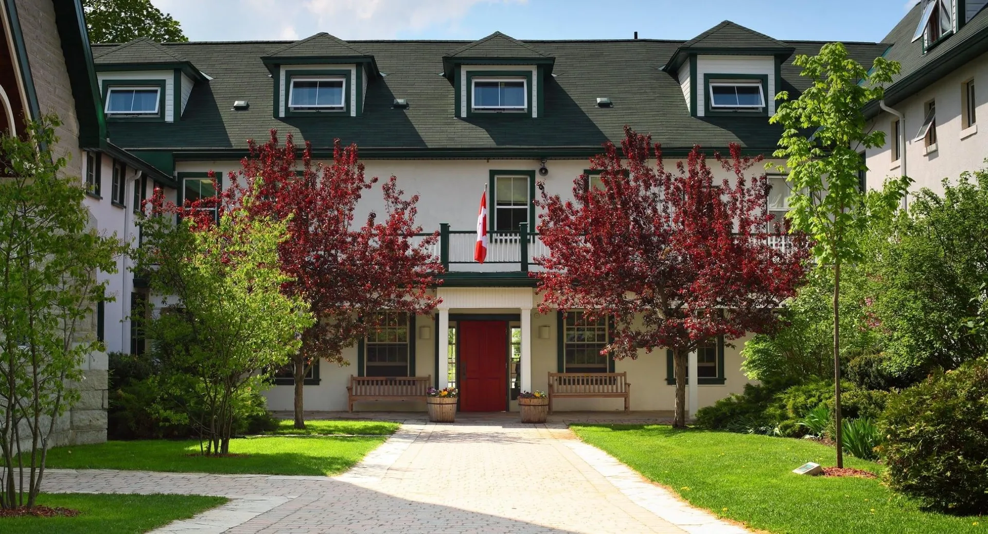 L'edificio a più piani con tetto verde della Lakefield College School è circondato da alberi verdi e rossi.