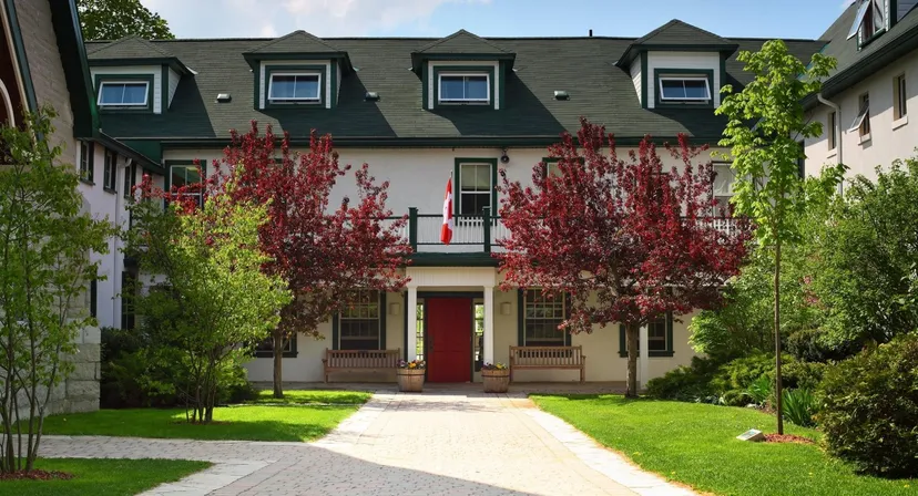 L'edificio a più piani con il tetto verde nel campus della Lakefield College School è circondato da vegetazione verde e rossa.