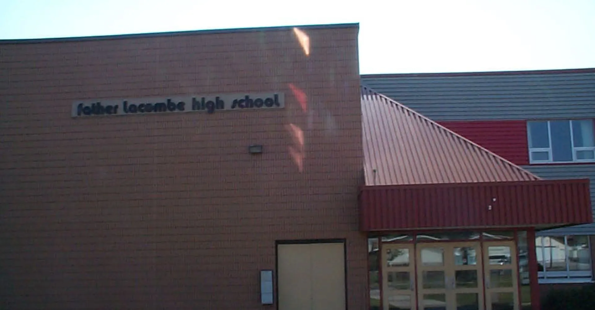 L'edificio scolastico moderno della Father Lacombe High School con facciata rossa e marrone e il nome della scuola sul davanti.