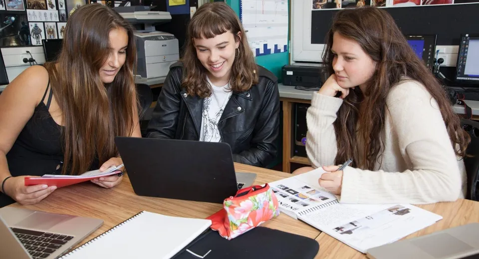 Tre studentesse del Western Springs College lavorano insieme a un laptop in un'aula studio.