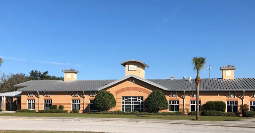 L'edificio in mattoni con tetto in metallo e ciminiere delle Marion County Public Schools è circondato da alberi e spazi verdi.
