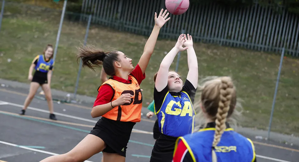 Due studentesse della Archbishop's School giocano una partita di netball sul campo della scuola.