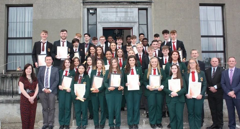 Un grande gruppo di studenti della Royal School Cavan si trova in abito formale davanti all'imponente edificio scolastico.