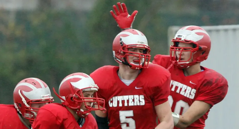 Un gruppo di giocatori di calcio in maglia rossa si trova sul campo da gioco della Gloucester High School.