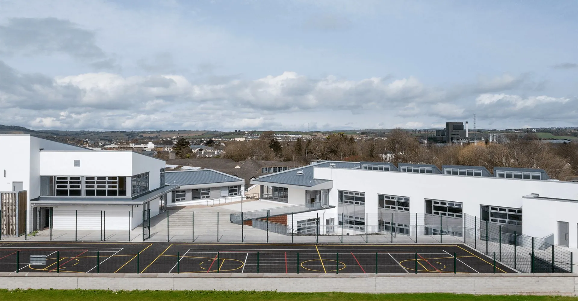 L'edificio moderno del St. Colman’s Community College si trova davanti a un paesaggio urbano collinare con un grande parcheggio in primo piano.