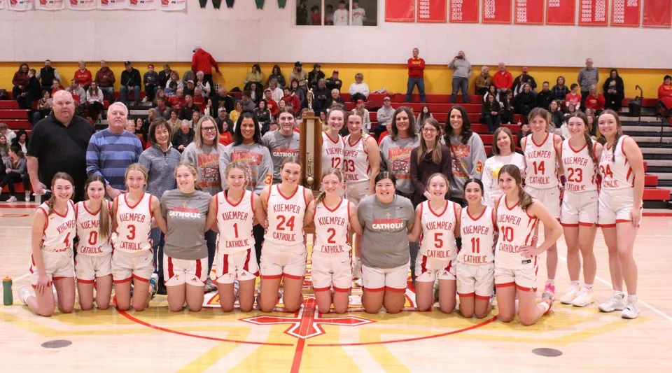 Un gruppo di studentesse della Kuemper Catholic High School posa sul campo da basket per una foto di squadra.