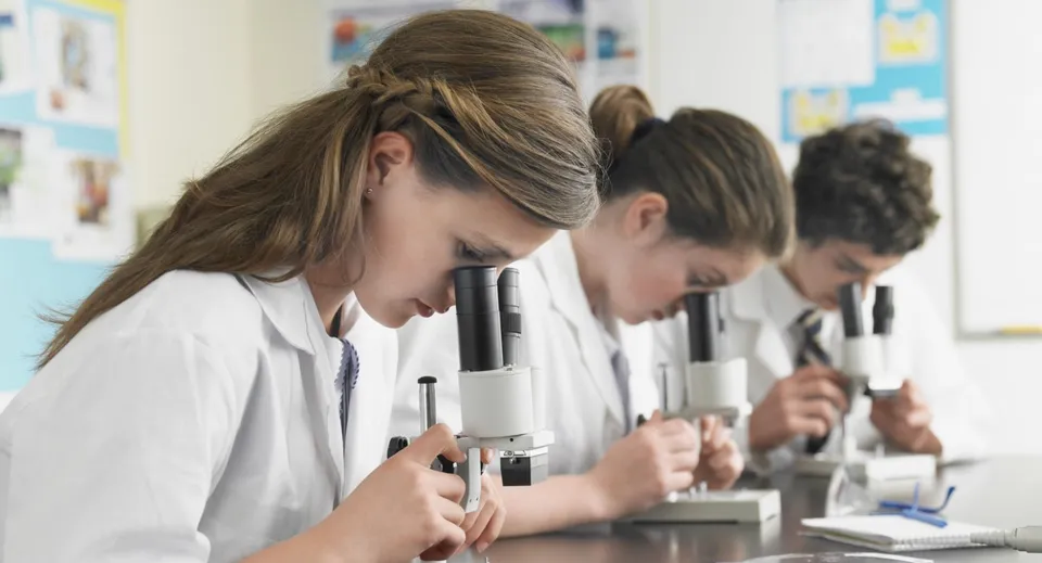 Studenti della Lord Tweedsmuir Secondary School lavorano concentrati con i microscopi durante la lezione di scienze.