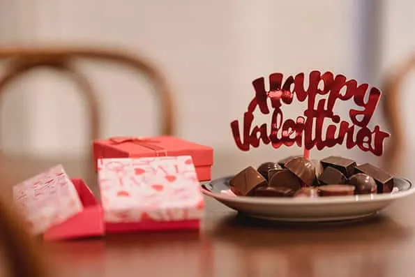 Plato con bombones de chocolate, cartel de Happy Valentine's y varias cajas de regalo