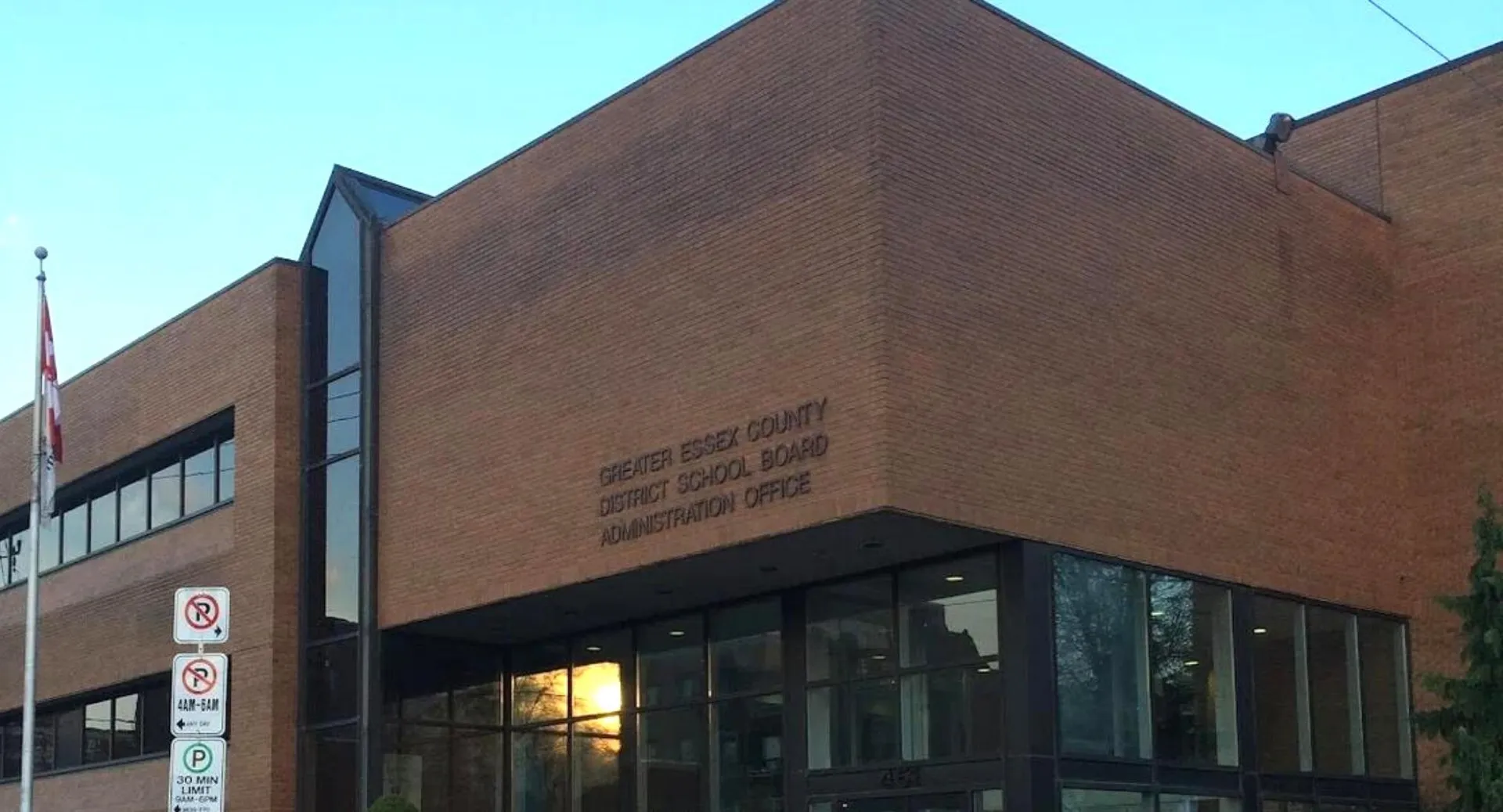 L'ampio edificio in mattoni con vetrate del Greater Essex County District School Board sotto un cielo azzurro e limpido.