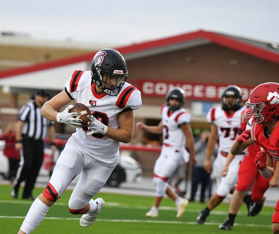 Un giocatore di football della Hillcrest High School corre con la palla in campo.