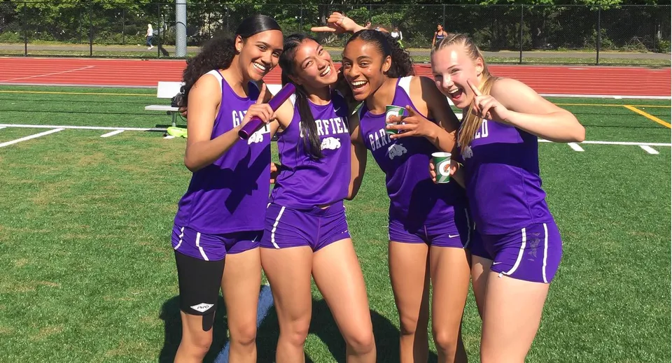Un gruppo di studentesse in uniformi viola posa sul campo sportivo delle Seattle Public Schools per una foto.