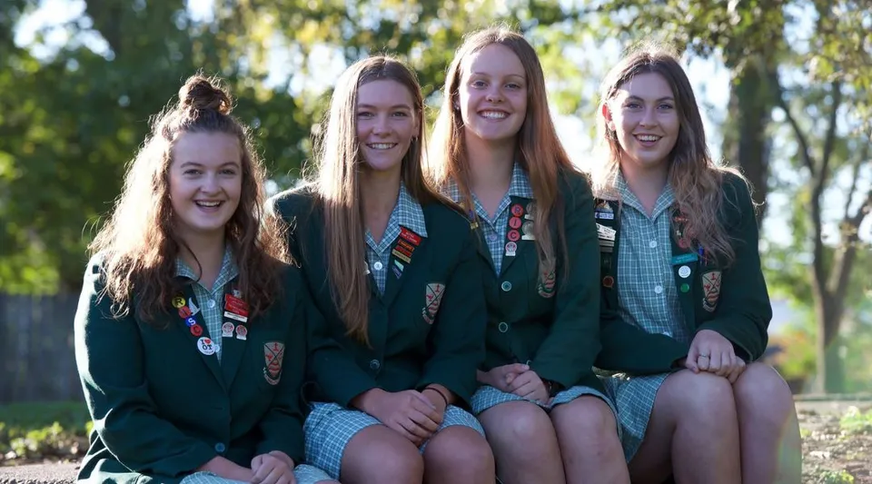 Studentesse della Avonside Girls' High School sono sedute insieme all'aperto, circondate dalla natura verde.