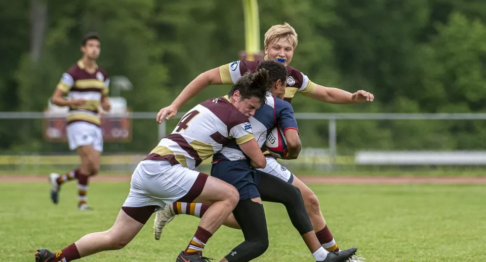 Giocatori di rugby della Dollar Academy durante un placcaggio nel corso di una partita sul campo verde.