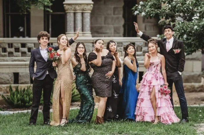 Ocho estudiantes con vestidos de gala y esmoquin lanzan besos antes del baile