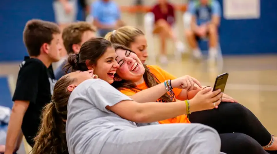 Un gruppo di studenti della Canterbury School si scatta un selfie insieme davanti a uno sfondo colorato.