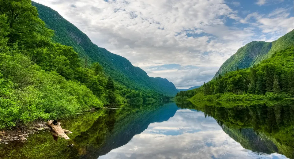 Un calmo lago di montagna con il riflesso del cielo e degli alberi nel tranquillo paesaggio vicino alla Lord Tweedsmuir Secondary School.