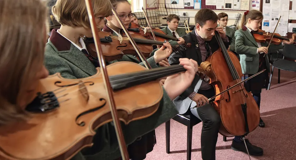 Un gruppo di musicisti della Oswestry School prova insieme in una stanza con strumenti musicali.