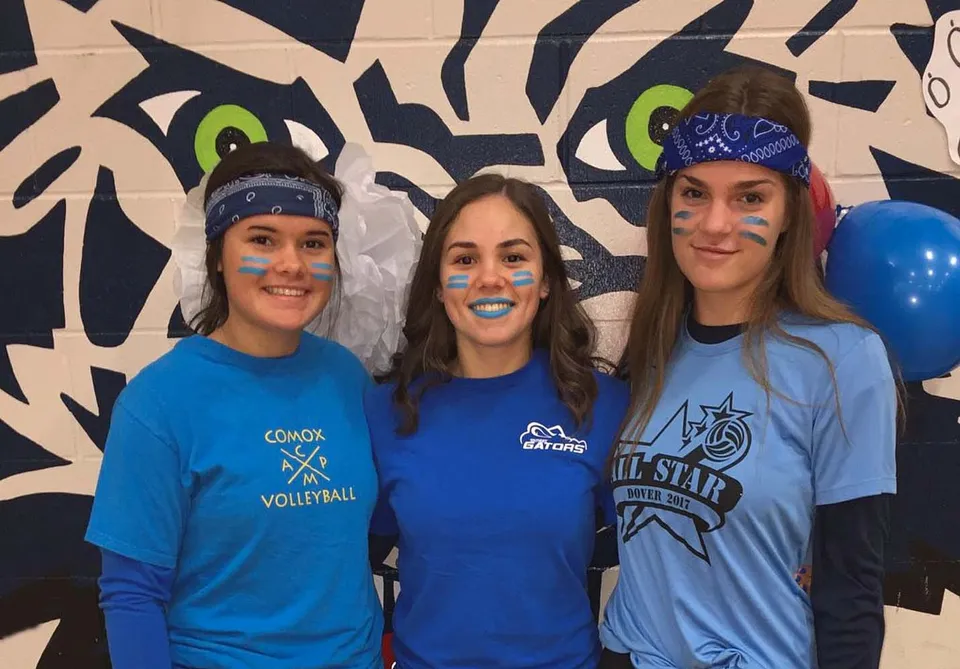 Tre studentesse della Timberline Secondary School posano davanti a uno sfondo con graffiti colorati.