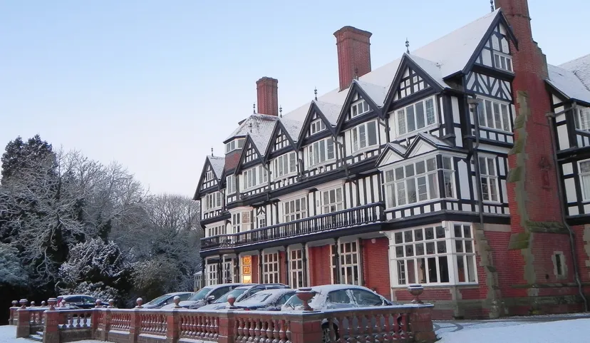 L'edificio storico in stile Tudor del Bedstone College è circondato da alberi innevati e da un cielo azzurro limpido.
