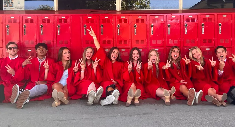 Studentesse della Whittier Christian High School siedono in divisa rossa davanti a una fila di armadietti rossi.