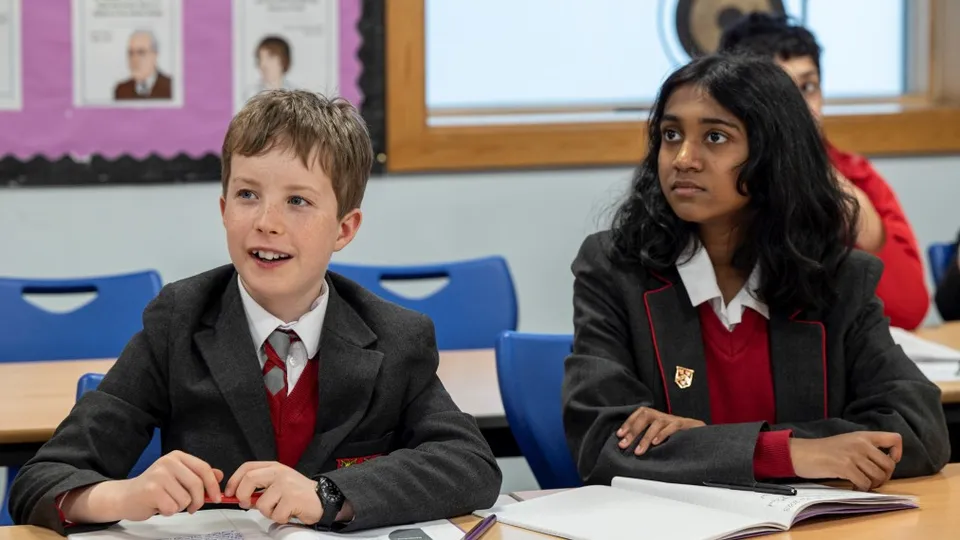 Due studenti della Kingston Grammar School in divisa scolastica siedono ai loro banchi in aula.