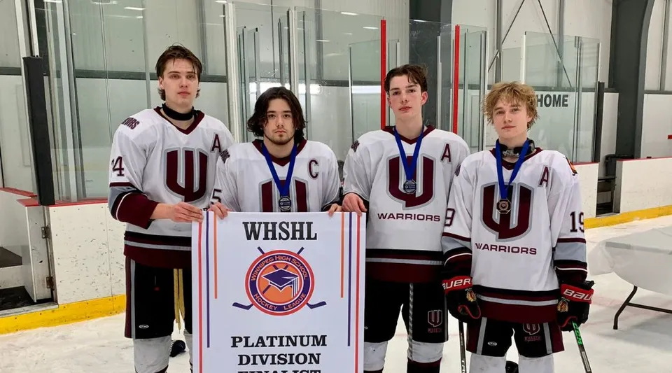 Un gruppo di giovani giocatori di hockey tiene uno striscione della WESHL Platinum Division davanti a una pista da ghiaccio alla Westwood Collegiate.