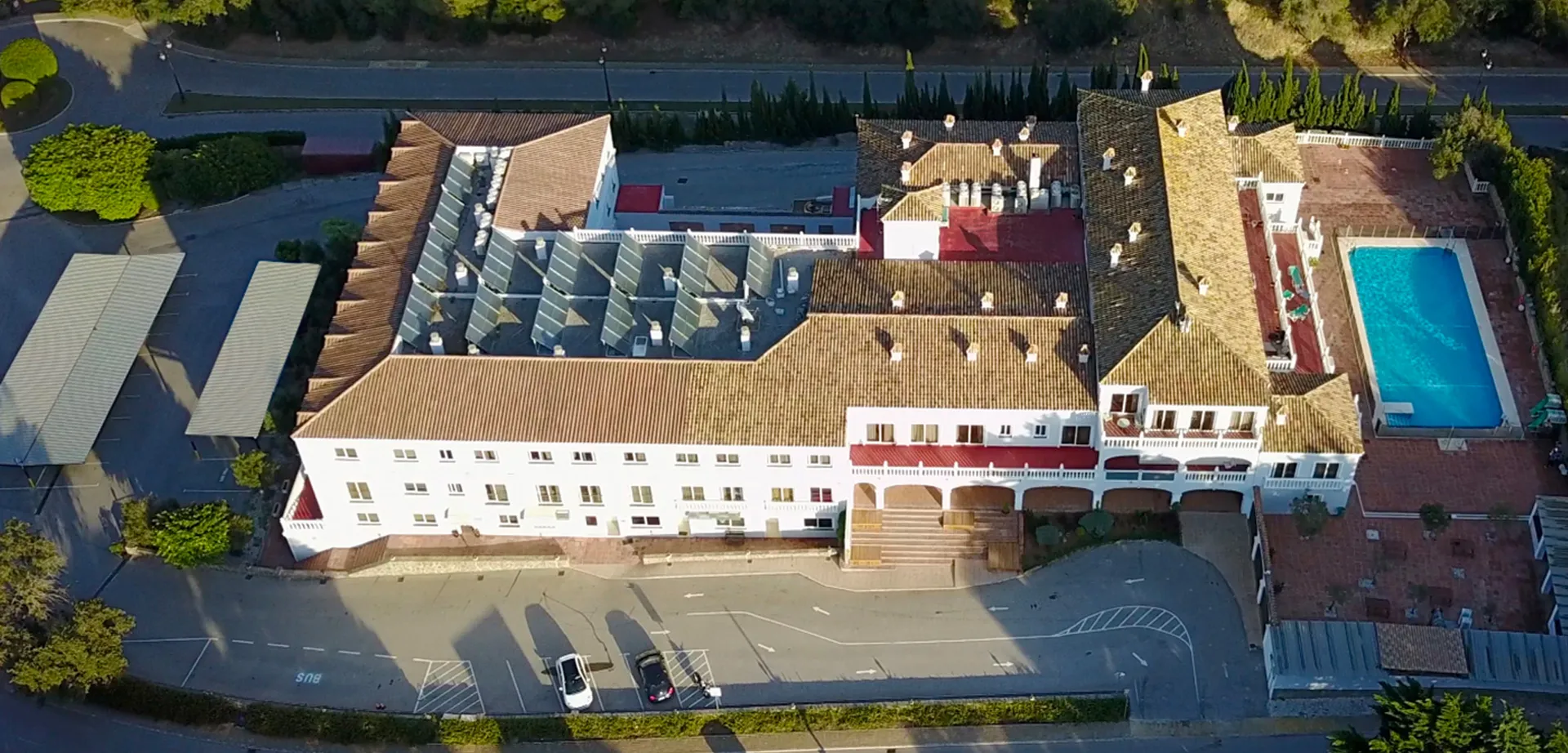 Veduta aerea di un grande edificio simile a un castello nel campus della Sotogrande International School con verde e acqua circostanti.