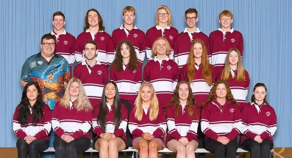Un gruppo di studenti e studentesse della Mount Compass Area School posa nella palestra indossando le uniformi scolastiche abbinate color bordeaux e bianco.