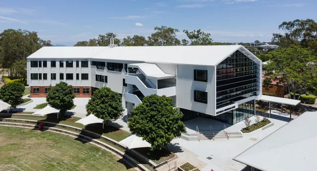 L'edificio moderno a più piani della Corinda State High School è circondato da alberi e aree verdi.