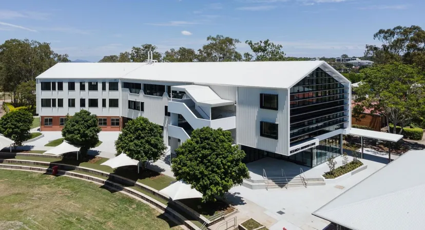 L'edificio moderno a più piani della Corinda State High School è circondato da alberi e aree verdi.