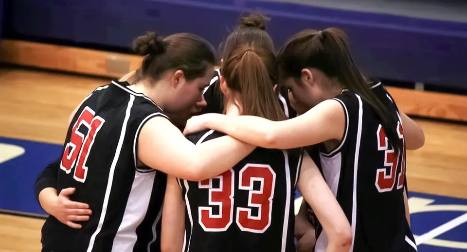 Un gruppo di giovani giocatrici di basket si abbraccia stretto sul campo da gioco della Dominion Academy of Dayton.