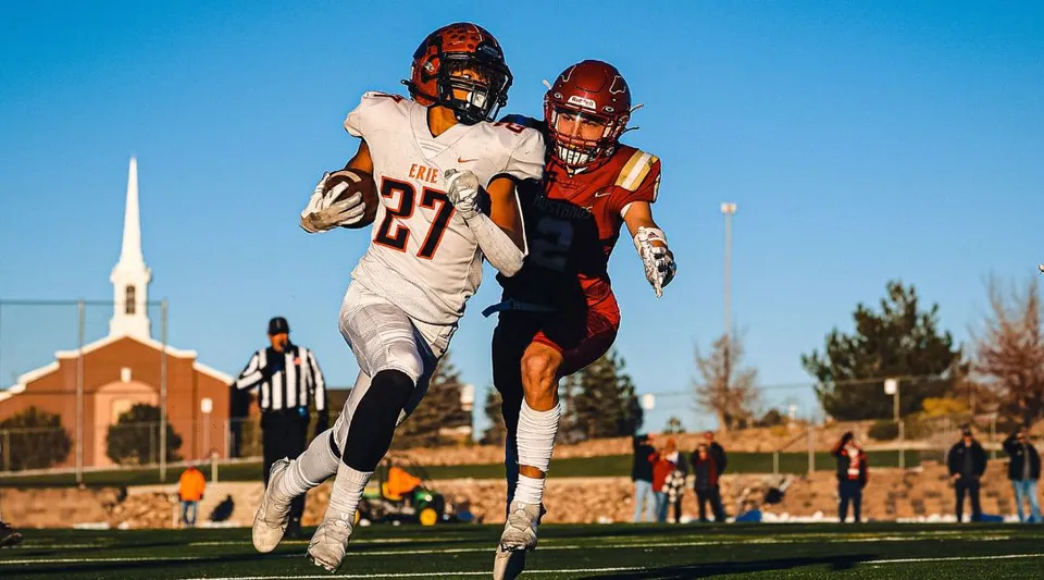 Un giocatore di football americano della Erie High School corre con la palla superando un avversario.