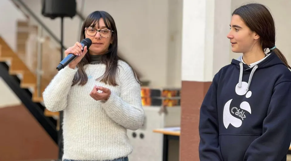 Due studentesse della Salesianas si trovano in un'aula scolastica con banchi e sedie sullo sfondo.