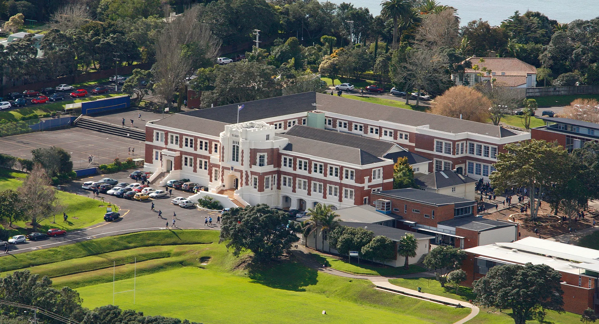 L'edificio in mattoni a più piani della Takapuna Grammar School si trova su una collina erbosa circondata da alberi.