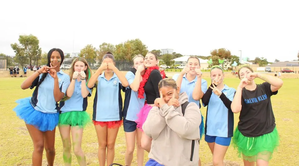 Un gruppo di giovani atlete posa su un campo erboso nel campus del Yanchep Secondary College.