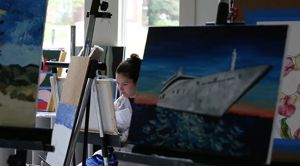 Uno studente dipinge su un cavalletto durante la lezione d'arte alla Garrison Forest School con materiale artistico nella stanza.