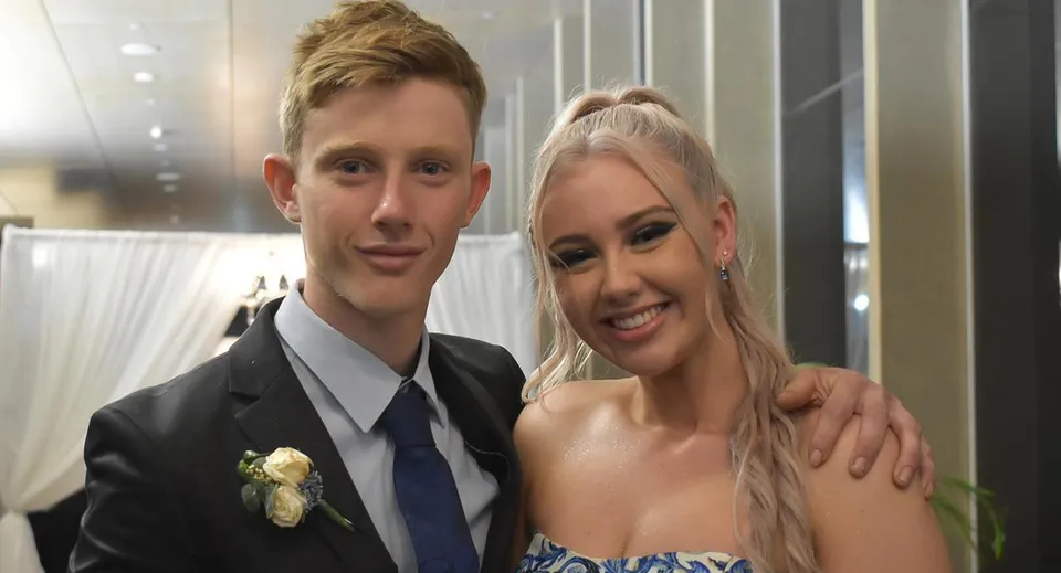 Una giovane coppia posa insieme in un'occasione formale nel campus della Mackay North State High School.