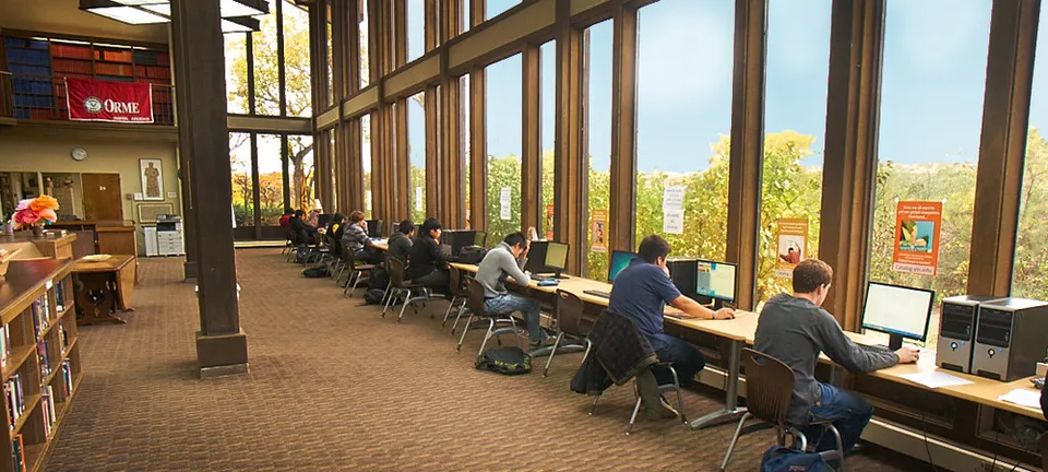 Postazione di lavoro con diversi studenti al computer in un'ampia stanza della The Orme School con vista sulla natura.