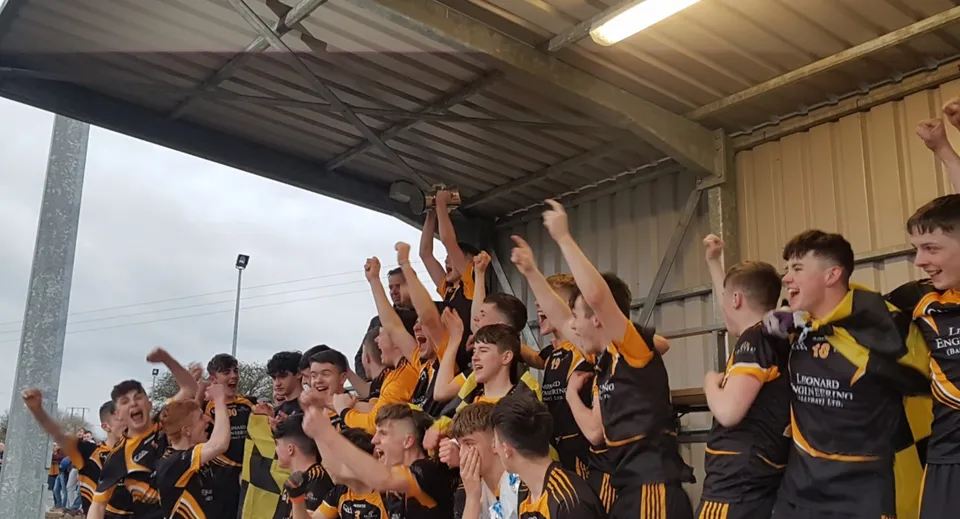 Gli studenti del Ballybay Community College alzano le braccia festeggiando insieme in una palestra.